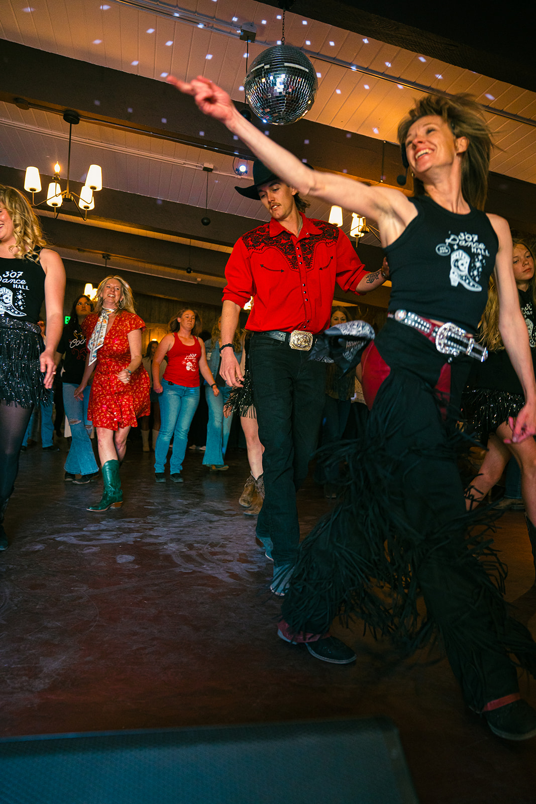 Line dance leader with arm out, room following